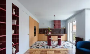 Cocina moderna con isla ovalada, estanterías rojas y suelo geométrico. Un ejemplo de **estudios interiorismo** audaces y coloridos.