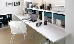 Un moderno despacho en buhardilla con un portátil, cámaras, impresora y una silla blanca.