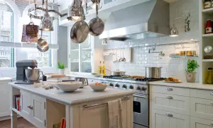 Cocinas clásicas con isla central, campana de acero inoxidable y utensilios colgando. Perfecta para crear platos deliciosos.