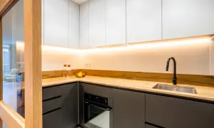 Cocinas negras y madera, con encimera de madera clara, armarios superiores blancos y detalles modernos.