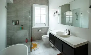 Baño moderno con ducha sin mampara, bañera exenta, lavabo sobre encimera y WC. Azulejos grises y suelo estampado.