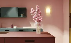 Elegante cocina rosa con encimeras de color burdeos, armarios verde azulado y un ramo de flores rosas.