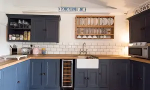 Cocina renovada sin obras: armarios azul marino, encimera de madera, fregadero blanco y suelo de baldosas a cuadros.