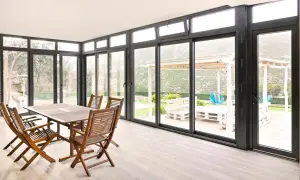Comedor interior con mesa de madera y sillas, conectado a un jardín con porche acristalado. Precio a consultar.