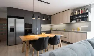 Moderna cocina abierta con isla de comedor, electrodomésticos integrados y estanterías para vinos.
