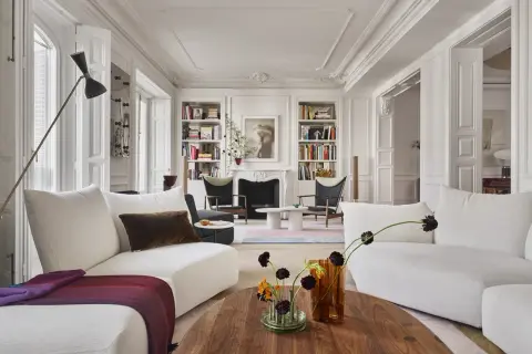 Elegante salón con sofás blancos, chimenea y estanterías, un ejemplo de un estudio de arquitectura e interiorismo.