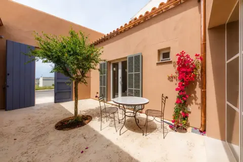 Un patio andaluz con mesa y sillas de hierro forjado, un árbol frutal y buganvillas. Ideas para un oasis mediterráneo.
