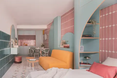 Un espacio moderno y colorido, ideal para saber como dar luz a una planta baja. Muebles curvos, estanterías y azulejos vibrantes crean un ambiente acogedor.
