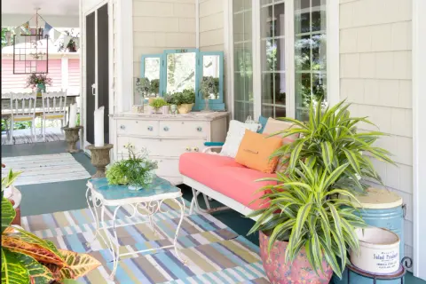 Porches sencillos y bonitos con un sofá coral, plantas exuberantes y un tocador vintage.