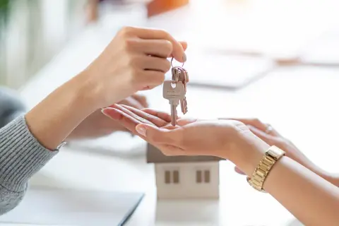Un asesor compra vivienda entrega las llaves de una casa modelo a un cliente.
