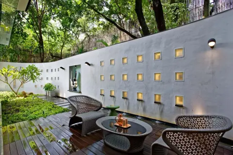 Elegante decoracion patio exterior con muebles de mimbre, cascadas y luces cálidas en la pared.