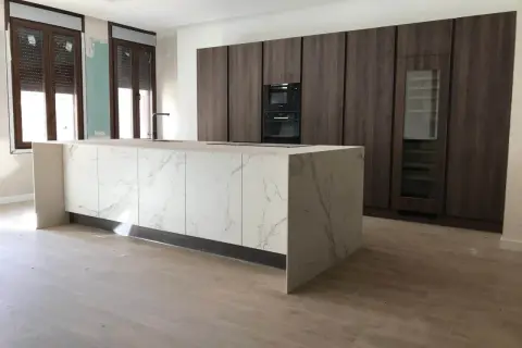 Cocinas modernas con barra central de mármol y gabinetes oscuros.