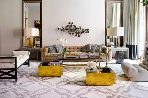 Sofá de terciopelo marrón, mesas doradas y alfombra geométrica crean una acogedora **conversation pit**.