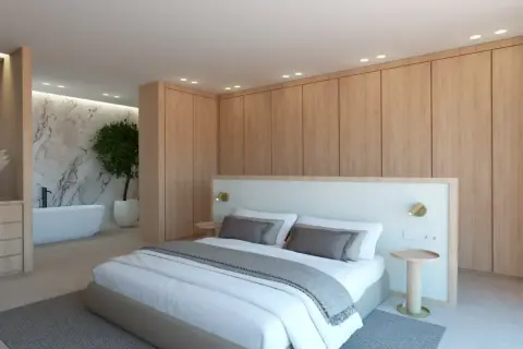 Dormitorio moderno con cama king size, armarios de madera y un baño suite con bañera exenta y pared de mármol.