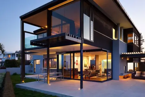Moderna casa prefabricada diseño, con amplios ventanales y terrazas, iluminada al atardecer.