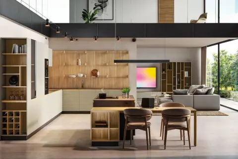 Moderna cocina con ventanal, estanterías de madera y una isla central. El espacio se abre a un salón con sofá y vistas al exterior.