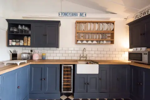 Cocina renovada sin obras: armarios azul marino, encimera de madera, fregadero blanco y suelo de baldosas a cuadros.