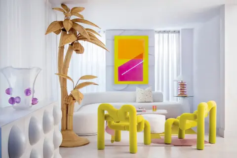 Sala de estar con vibrante arte abstracto, muebles curvos y un árbol de mimbre, todo con un audaz estilo Memphis.