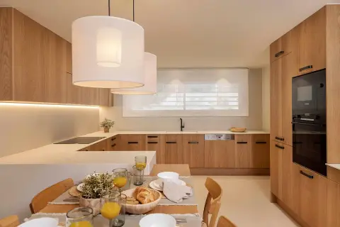 Cocina moderna con gabinetes de madera clara, encimeras blancas y una isla. Perfecta para tus ideas de cocinas.