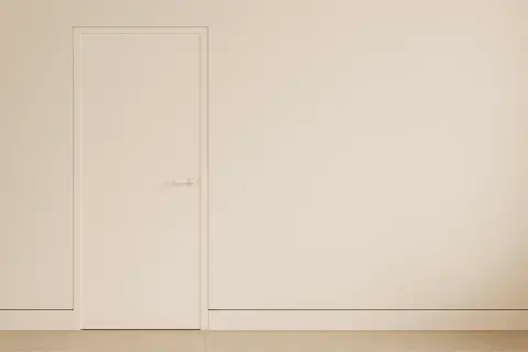 Puerta blanca minimalista con manija discreta y un rodapié enrasado que se funde con la pared, creando un espacio limpio y moderno.