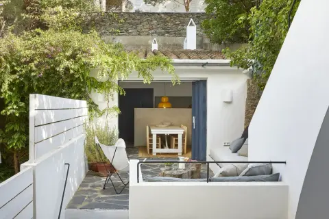 Un moderno patio andaluz con muebles blancos, vegetación exuberante y un rincón acogedor para relajarse.
