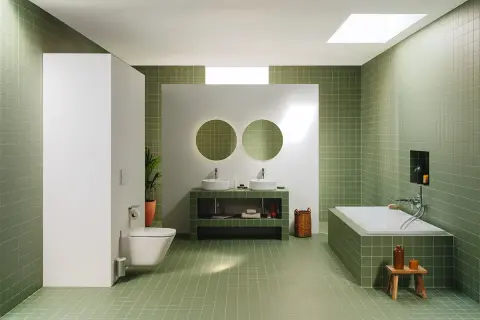 Moderno baño con azulejos verdes, doble lavabo, bañera y WC. Un espacio ideal para renovar el baño con estilo y funcionalidad.