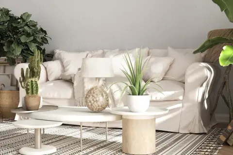 Sofá blanco, plantas, maletas vintage y alfombra geométrica crean un ambiente de **estilo rústico moderno**.