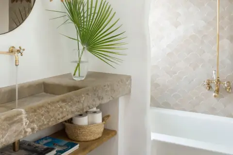 Elegante lavabo de piedra natural y grifería dorada, parte de una cuidada decoracion cuartos de baño con azulejos de escamas.