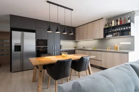 Moderna cocina abierta con isla de comedor, electrodomésticos integrados y estanterías para vinos.