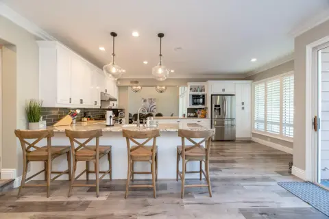 Cocinas abiertas al salón pequeñas con isla central, taburetes de madera y electrodomésticos modernos.