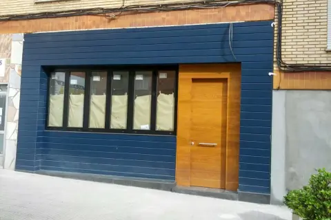 Fachadas de locales convertidos en viviendas, con puerta de madera y ventanas cubiertas.
