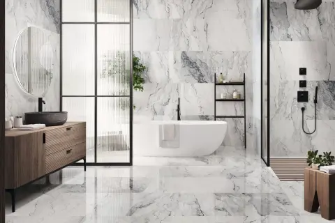Elegantes combinaciones de azulejos para baños con efecto mármol, bañera exenta y mueble de madera.