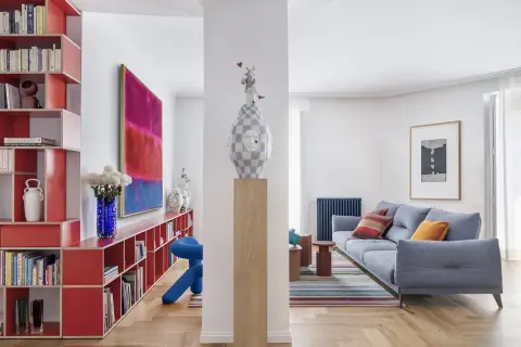 Estudios de arquitectura: sala de estar moderna con sofá azul, alfombra de rayas, estanterías rojas y arte abstracto.