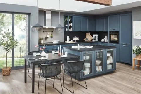 Cocinas con isla en azul marino, con encimera oscura, mesa de comedor y sillas negras. Ventanal grande con vistas al jardín.