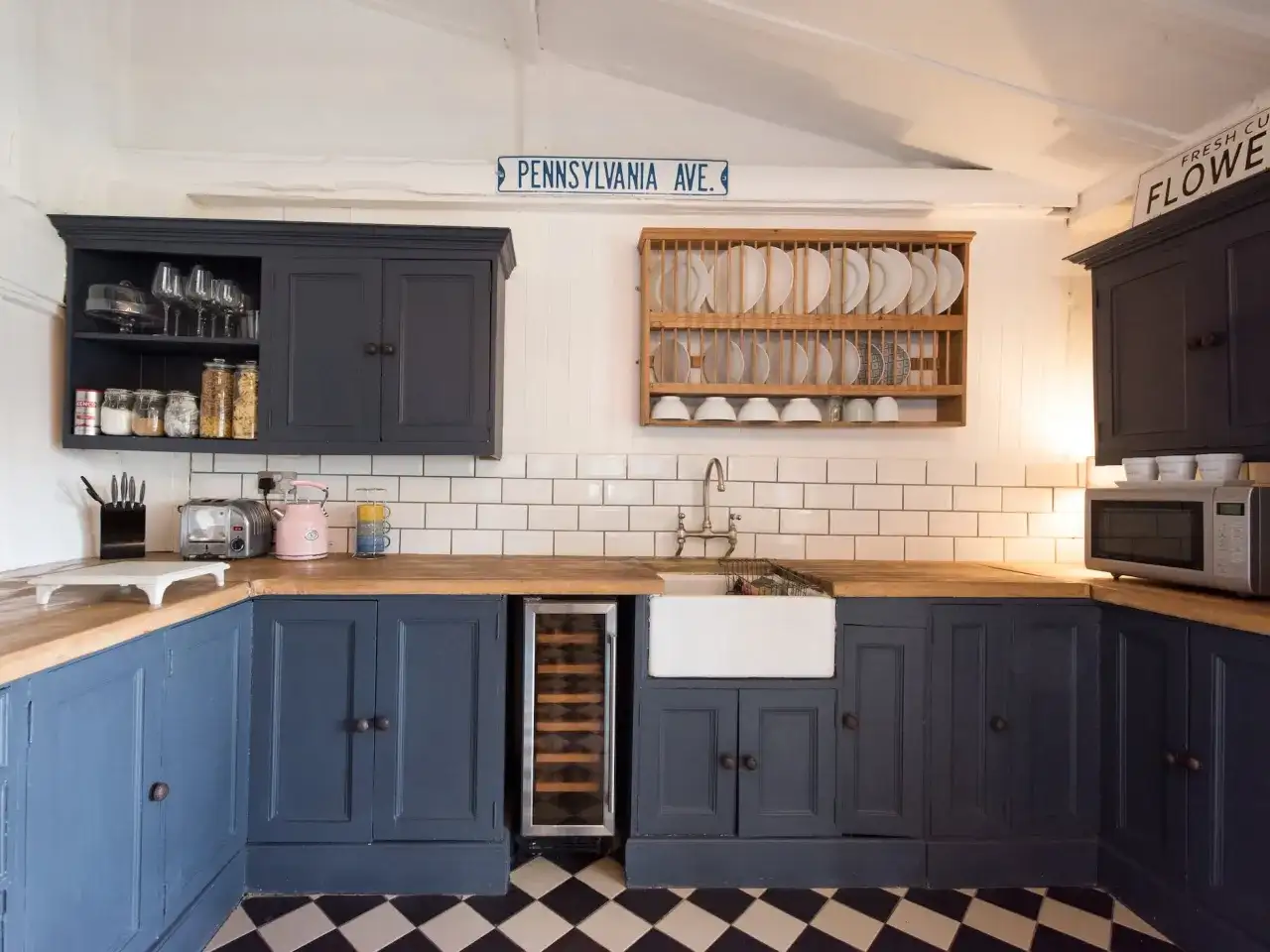 Cocina renovada sin obras: armarios azul marino, encimera de madera, fregadero blanco y suelo de baldosas a cuadros.