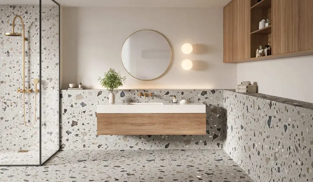 Baño moderno con azulejos de terrazo, una ducha dorada y un lavabo flotante. Las tendencias azulejos baño apuestan por este estilo.