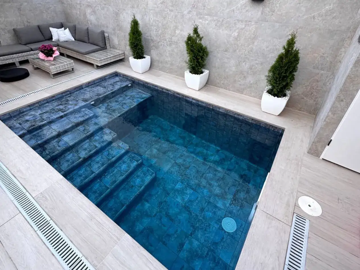 Un rincón de paz con piscinas pequeñas con encanto, rodeadas de vegetación y un cómodo sofá para relajarse.