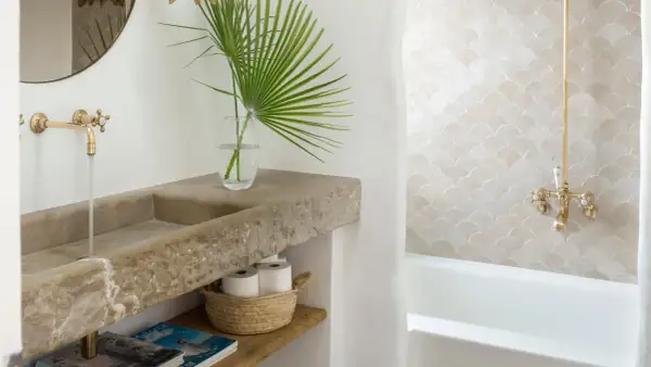 Elegante lavabo de piedra natural y grifería dorada, parte de una cuidada decoracion cuartos de baño con azulejos de escamas.