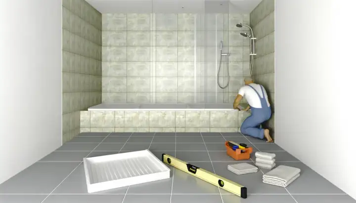 Un obrero instala una bañera de obra. Herramientas y toallas esperan en el suelo.